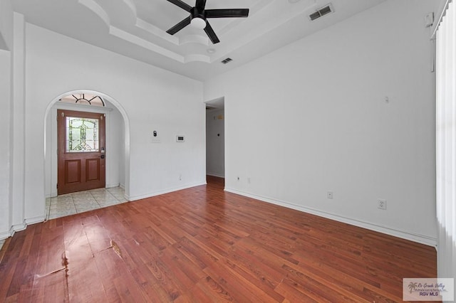 4217 W Ithaca Ave, Mcallen, TX 78501 - empty room featuring arched walkways, a ceiling fan, a tray ceiling, wood finished floors, and baseboards