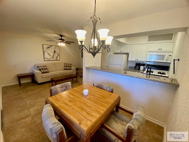 tiled dining space featuring baseboards, visible vents, and ceiling fan with notable chandelier