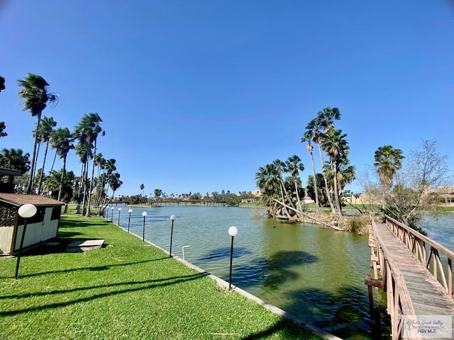 view of dock with a water view and a yard