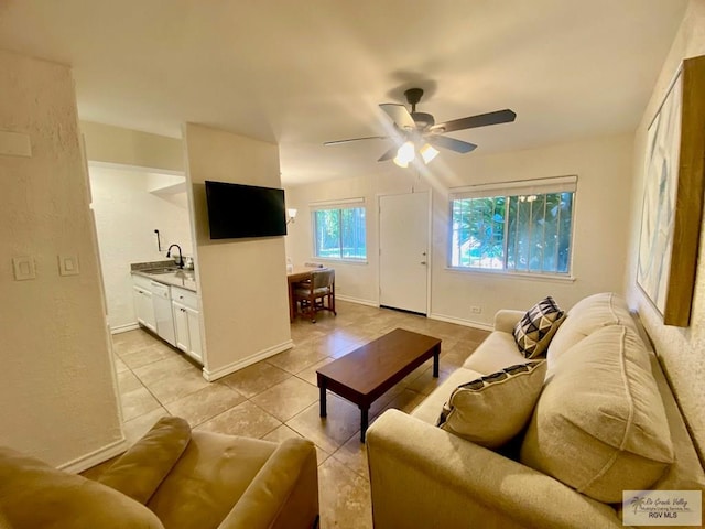 living area featuring a ceiling fan, baseboards, and light tile patterned floors