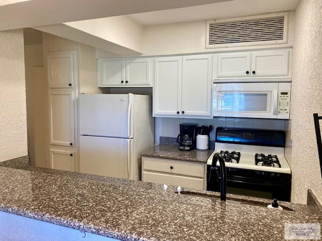 kitchen with white appliances, tasteful backsplash, visible vents, dark stone counters, and white cabinetry