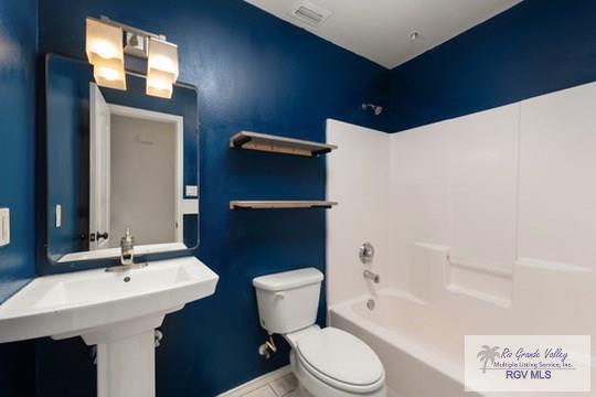 18186 King Palm Dr, Harlingen, TX 78552 - full bathroom with toilet, washtub / shower combination, tile patterned floors, and baseboards