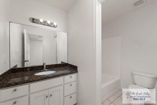 18186 King Palm Dr, Harlingen, TX 78552 - bathroom featuring toilet, vanity, tile patterned flooring, and washtub / shower combination