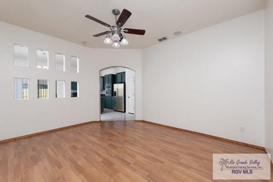 18186 King Palm Dr, Harlingen, TX 78552 - empty room featuring light wood-style floors, ceiling fan, arched walkways, and baseboards