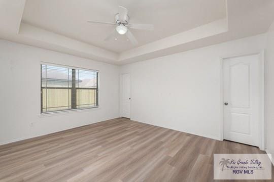 18186 King Palm Dr, Harlingen, TX 78552 - spare room with a tray ceiling, wood finished floors, and ceiling fan