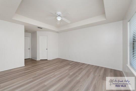 18186 King Palm Dr, Harlingen, TX 78552 - empty room with a raised ceiling, wood finished floors, and a ceiling fan