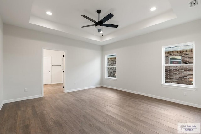 spare room with a raised ceiling, ceiling fan, and hardwood / wood-style flooring