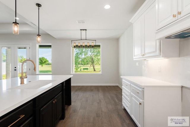 kitchen featuring sink, white cabinets, dark wood-type flooring, and decorative light fixtures