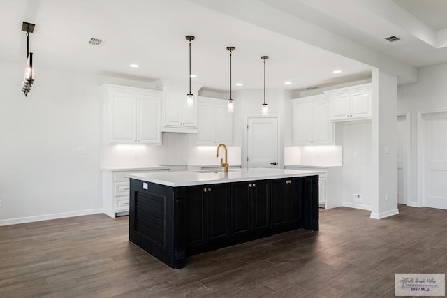 kitchen with white cabinetry, dark hardwood / wood-style flooring, an island with sink, and sink