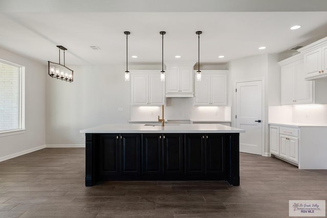 kitchen featuring white cabinets, dark hardwood / wood-style flooring, and a center island with sink