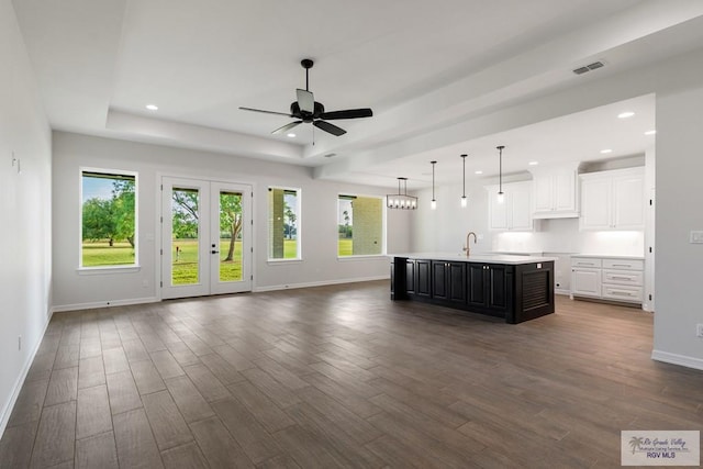 kitchen with dark hardwood / wood-style flooring, ceiling fan, sink, white cabinetry, and an island with sink