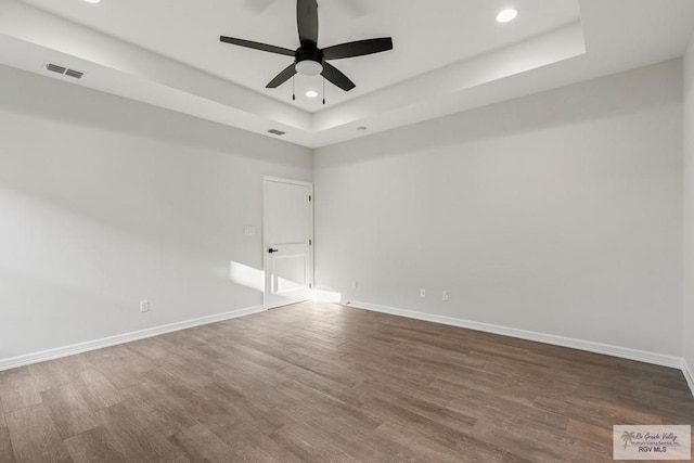 spare room featuring ceiling fan, wood-type flooring, and a tray ceiling