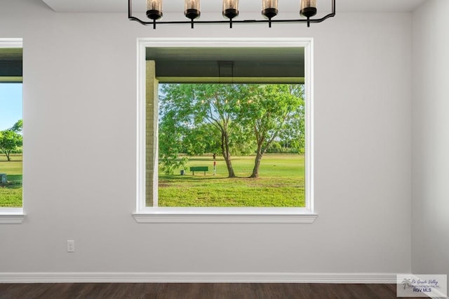 interior space with a wealth of natural light, dark wood-type flooring, and a notable chandelier