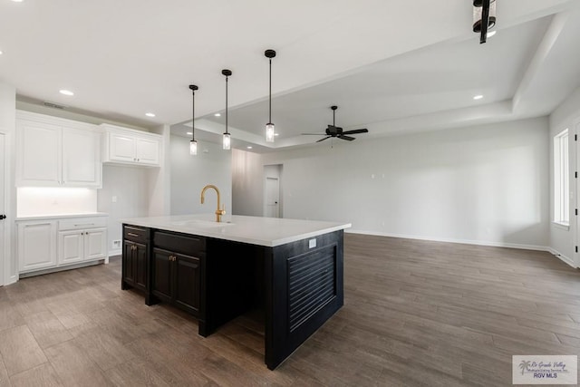 kitchen with ceiling fan, sink, hardwood / wood-style floors, an island with sink, and white cabinets