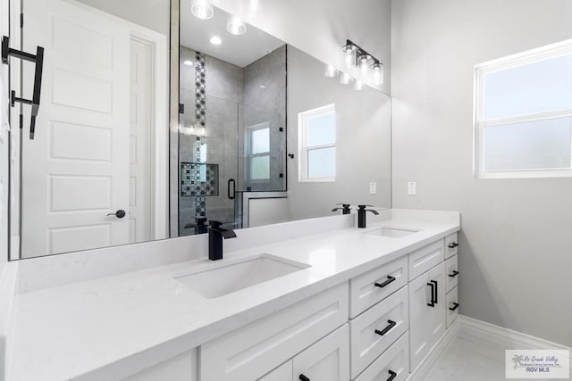 full bath featuring a sink, baseboards, double vanity, and a stall shower