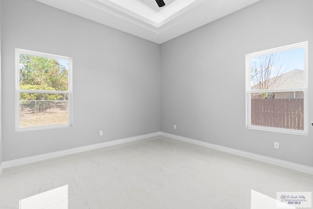 spare room with a wealth of natural light, ceiling fan, and baseboards