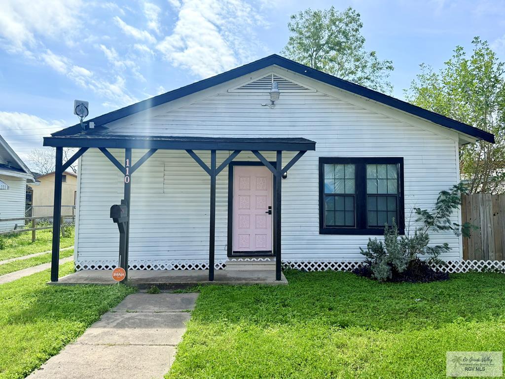 110 E Washington Ave, Harlingen, TX 78550 - bungalow-style house with entry steps, fence, and a front lawn