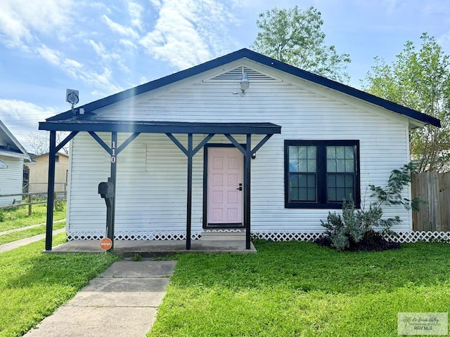 bungalow-style house with entry steps, fence, and a front lawn