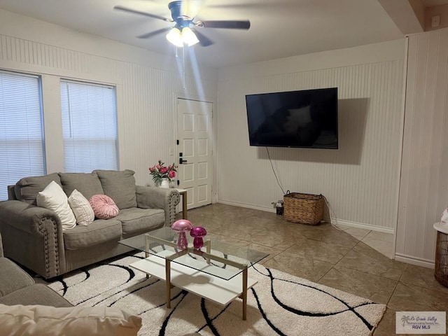 living room with a ceiling fan, baseboards, and light tile patterned floors