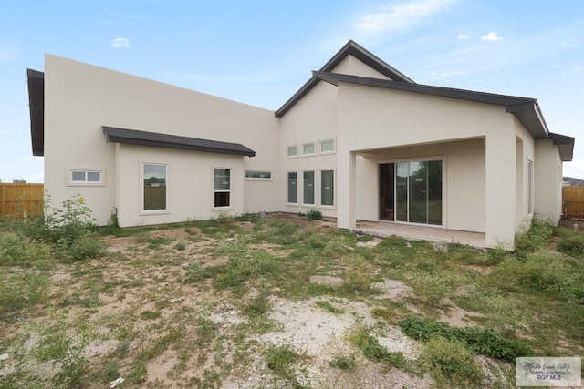 back of house with fence and stucco siding