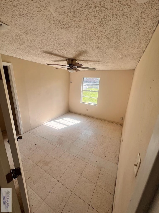 unfurnished room with ceiling fan and a textured ceiling