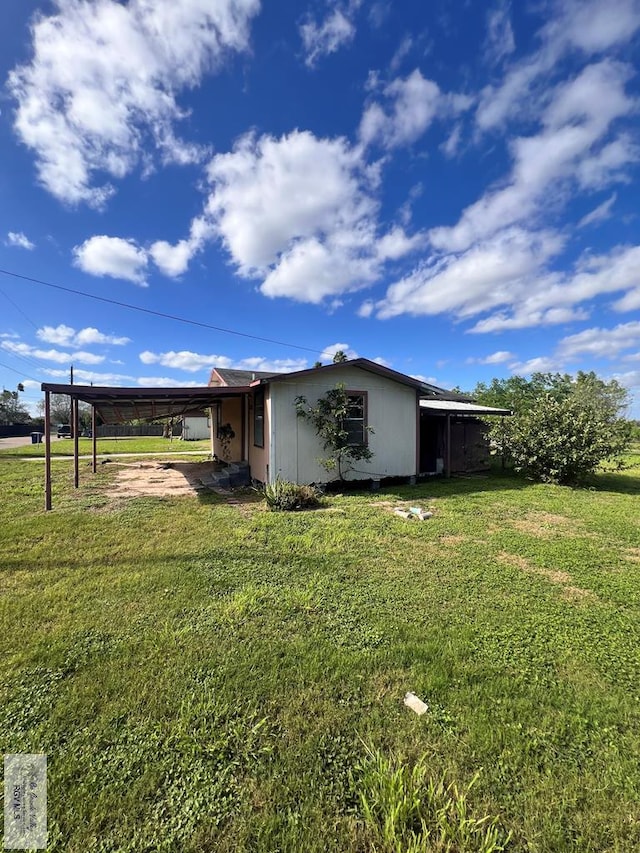 exterior space with a carport and a lawn