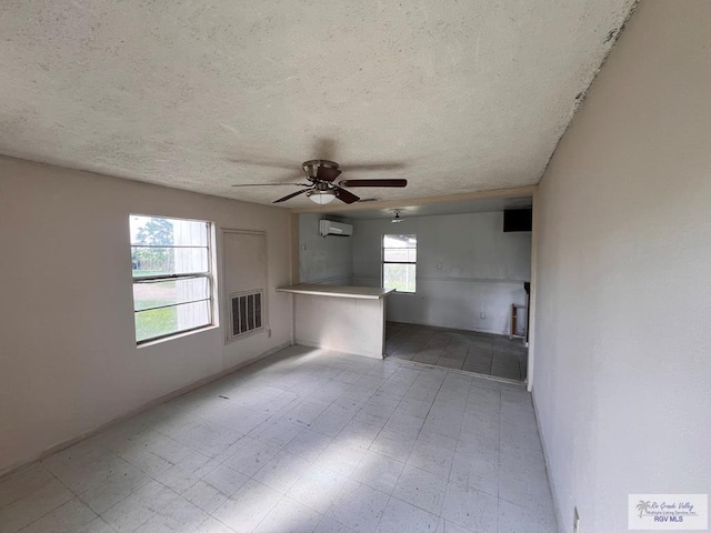 unfurnished room featuring ceiling fan, a textured ceiling, and an AC wall unit