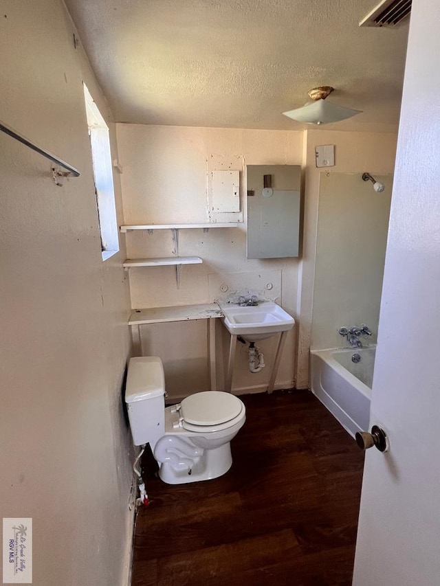 bathroom with wood-type flooring, toilet, and a textured ceiling