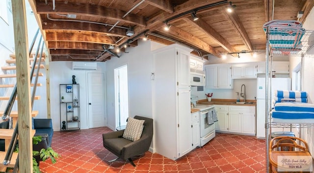 kitchen with wooden ceiling, beamed ceiling, a wall mounted AC, white appliances, and white cabinets