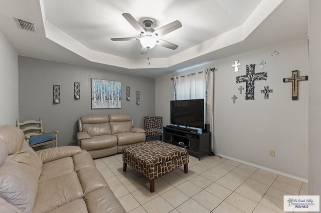 living room with ceiling fan, light tile patterned floors, and a tray ceiling