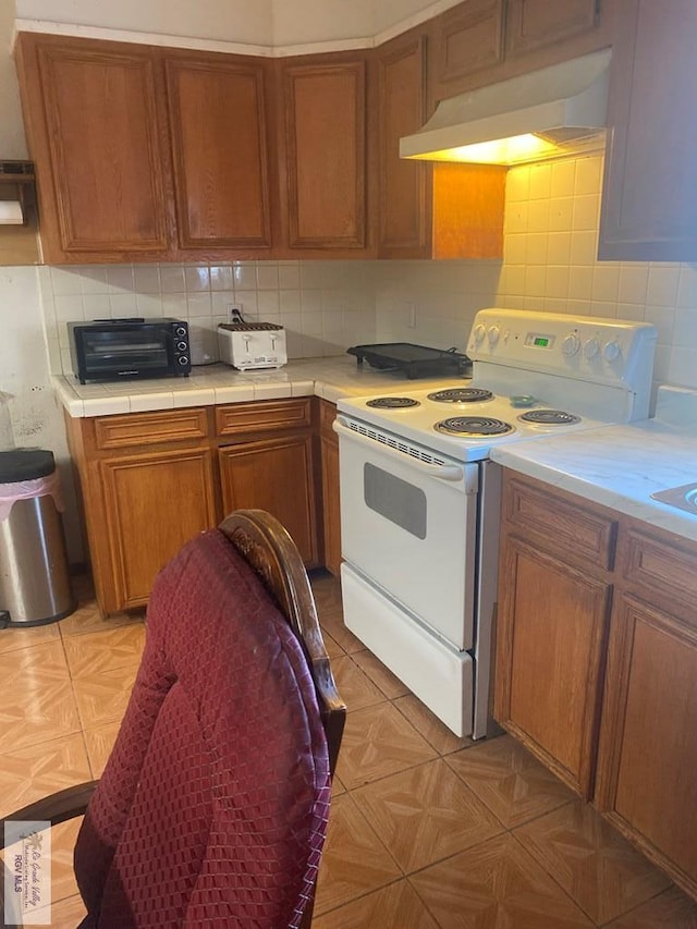 kitchen featuring white electric range oven, tasteful backsplash, and tile counters