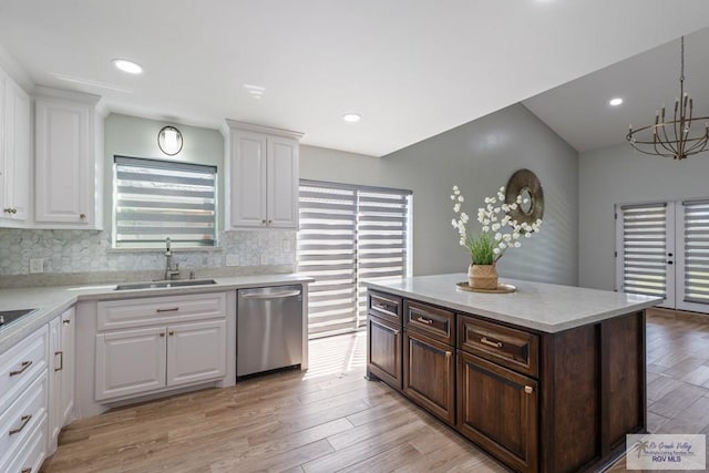 kitchen with a sink, white cabinets, light countertops, and dishwasher