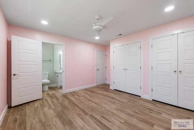 unfurnished bedroom with baseboards, light wood-style floors, visible vents, and multiple closets