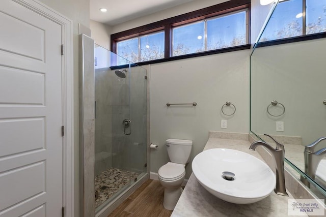 bathroom featuring a stall shower, baseboards, toilet, wood finished floors, and vanity