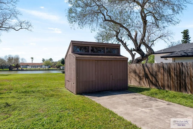 view of shed with a water view and fence