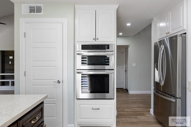 kitchen featuring light countertops, visible vents, appliances with stainless steel finishes, white cabinets, and light wood-type flooring