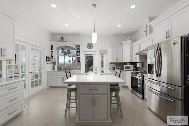 kitchen featuring stainless steel appliances, tasteful backsplash, pendant lighting, a kitchen bar, and white cabinets