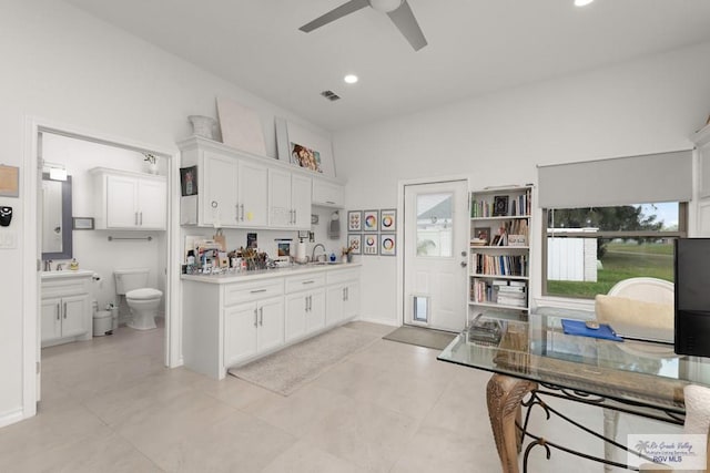 kitchen with ceiling fan, white cabinetry, and sink