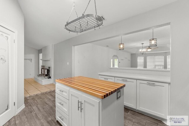 1000 E Palm Valley Dr, Palm Valley, TX 78552 - kitchen featuring white cabinets, a multi sided fireplace, butcher block countertops, vaulted ceiling, and wood finished floors