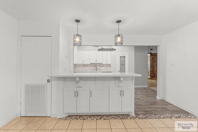 1000 E Palm Valley Dr, Palm Valley, TX 78552 - kitchen with a peninsula, light countertops, white cabinetry, light tile patterned floors, and pendant lighting