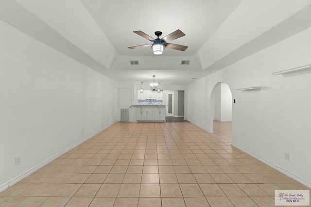 1000 E Palm Valley Dr, Palm Valley, TX 78552 - unfurnished living room featuring a ceiling fan, a chandelier, arched walkways, light tile patterned floors, and a raised ceiling