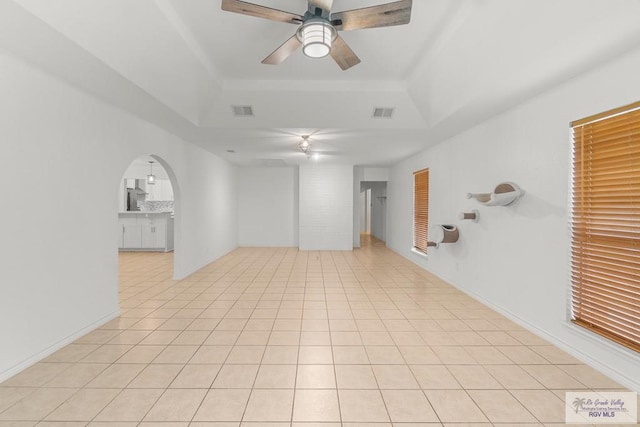 1000 E Palm Valley Dr, Palm Valley, TX 78552 - unfurnished room with a tray ceiling, ceiling fan, arched walkways, and light tile patterned floors
