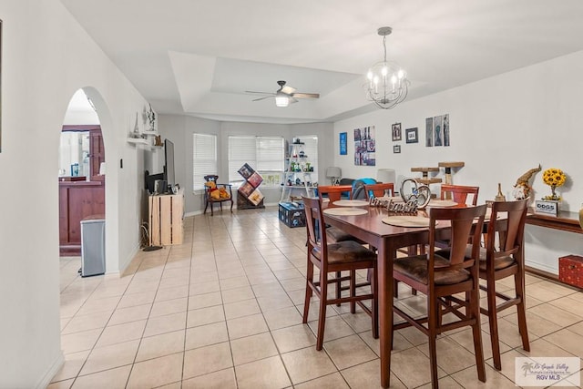 1000 E Palm Valley Dr, Palm Valley, TX 78552 - dining space featuring ceiling fan, light tile patterned flooring, arched walkways, a tray ceiling, and a chandelier
