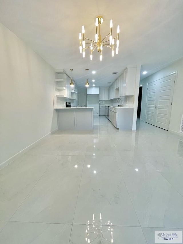 kitchen featuring kitchen peninsula, sink, a notable chandelier, white cabinetry, and hanging light fixtures