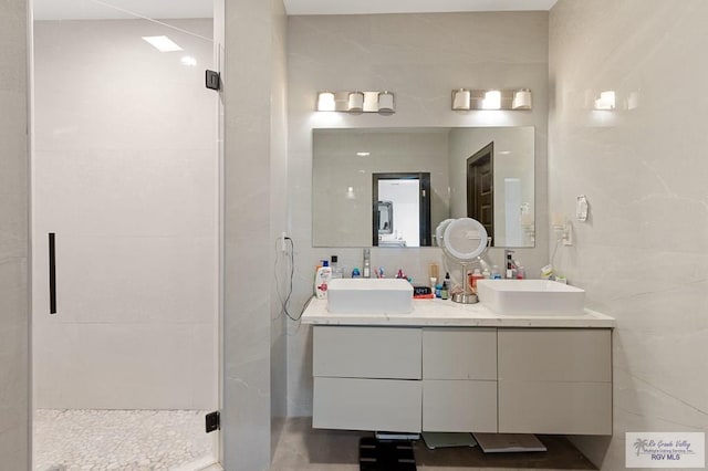 bathroom featuring a shower with door, vanity, and tile walls