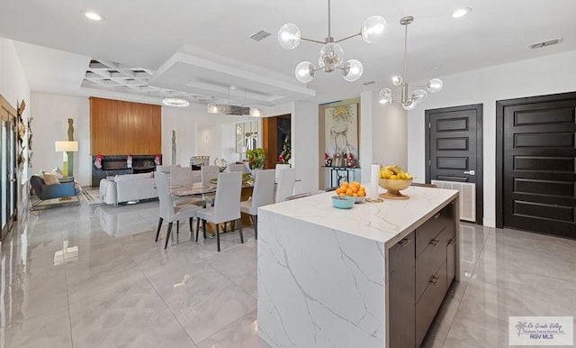 kitchen featuring a tray ceiling, a center island, pendant lighting, and an inviting chandelier