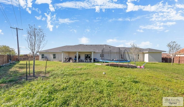 back of property with a lawn and a trampoline