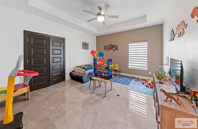 rec room with a raised ceiling and ceiling fan