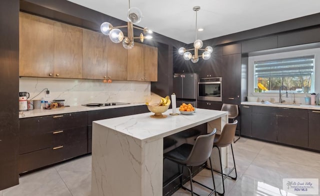 kitchen with light stone countertops, sink, a center island, pendant lighting, and appliances with stainless steel finishes