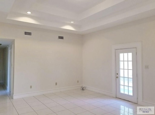 empty room with a raised ceiling and light tile patterned floors